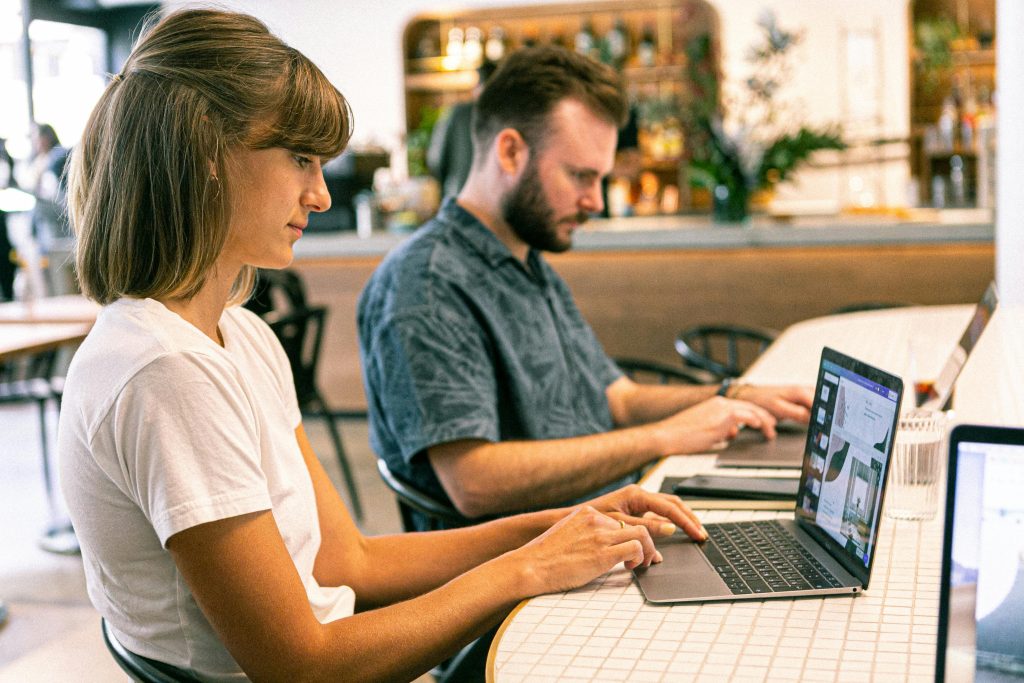 pexels-photo-3194518-3194518 Two young professionals working on laptops in a modern cafe setting.